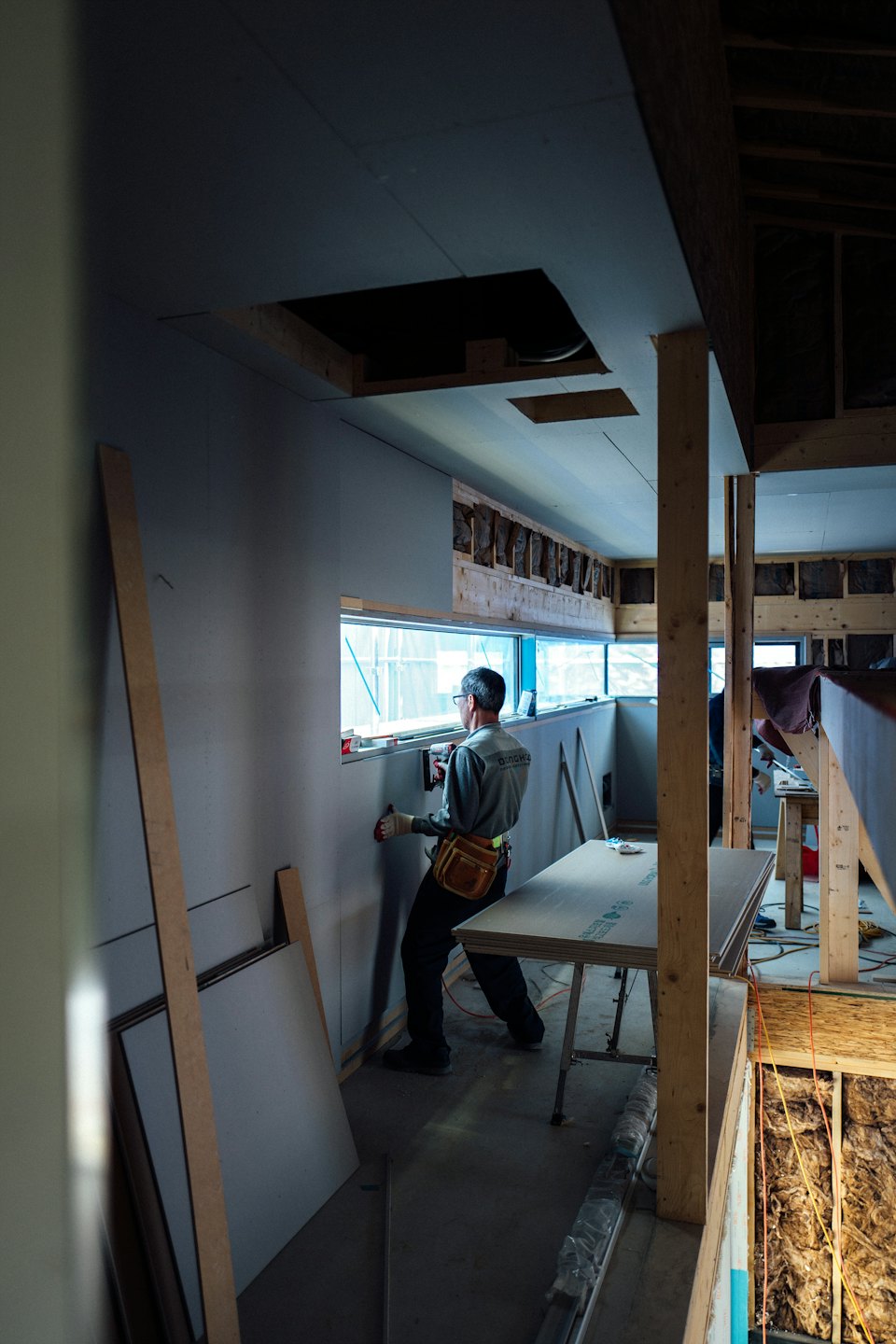 Construction worker installs drywall inside a building.