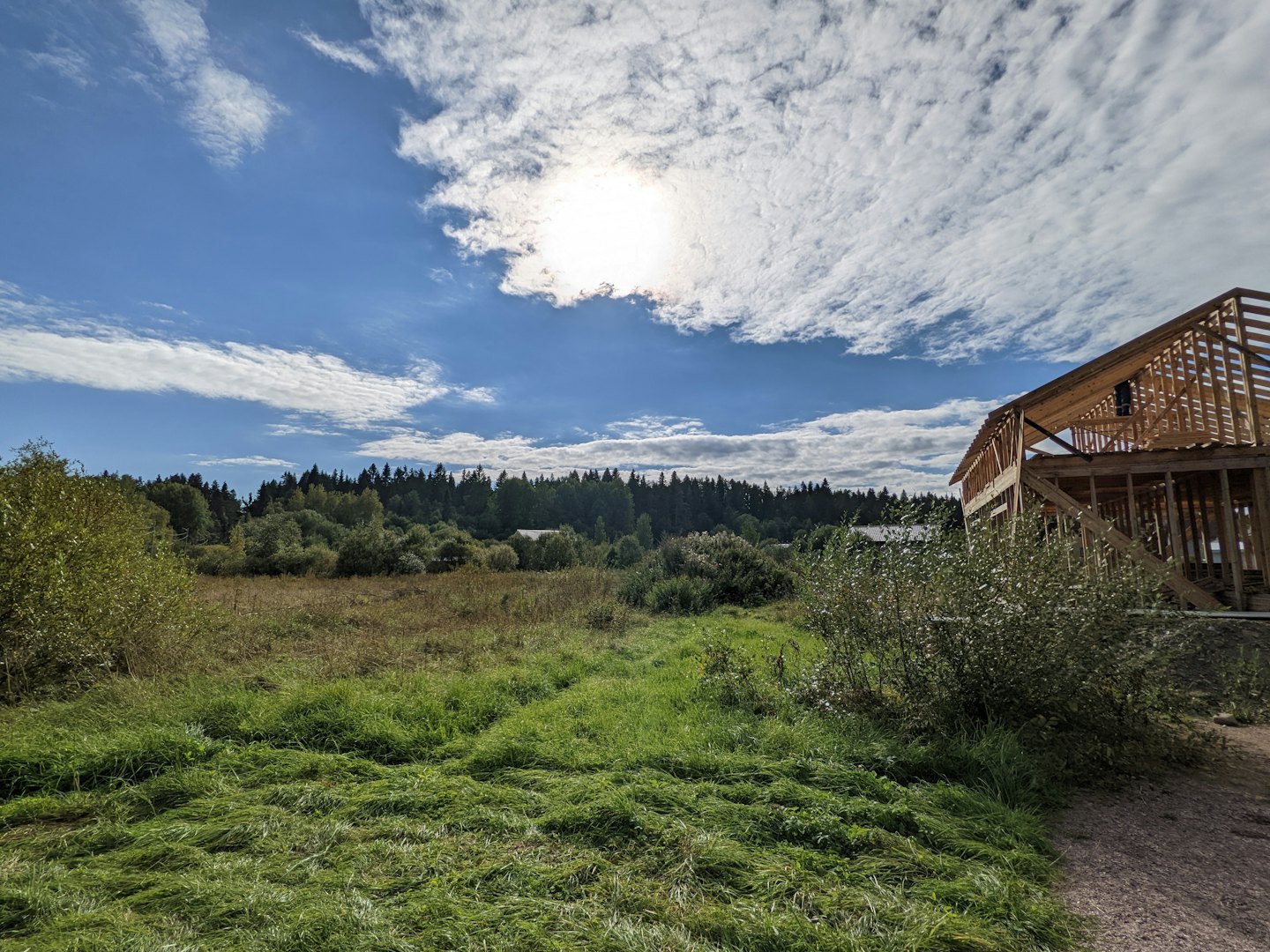 A construction worker builds a wooden house frame in a field.